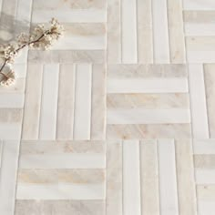 a marble tile floor with white and beige stripes on the tiles, as well as a flower