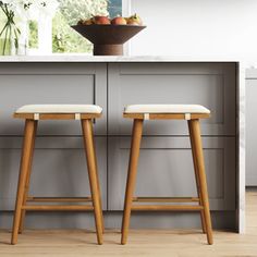 two stools sitting in front of a counter with fruit on the top and below