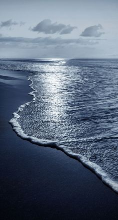 an ocean beach with waves coming in and the sun reflecting on the water's surface