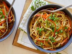 two bowls filled with noodles, carrots and green onions