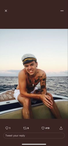 a man sitting on top of a boat next to the ocean with his arms crossed