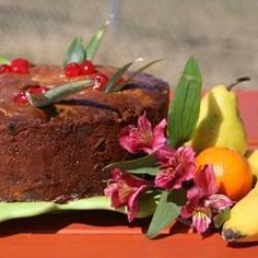 there is a cake with fruit on the plate next to it and flowers in front of it