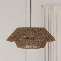 a hanging lamp made out of wicker in front of a white wall and curtains