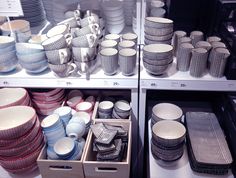 several shelves filled with dishes and cups on top of eachother, in a store