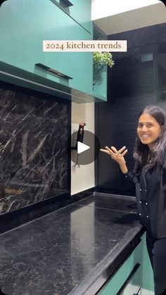 a woman standing in front of a black counter top