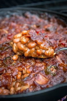 a spoonful of beans is being used to stir them in the skillet on the stove