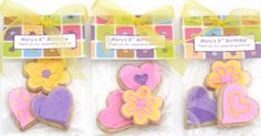 three decorated cookies in plastic wrappers with bows and ribbons on the top one has a name tag that says may's birthday, mary's 8 birthday