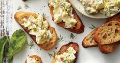 several pieces of bread with different types of food on them and garnished with herbs