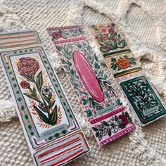 four decorative bookmarks laying on top of a white blanket