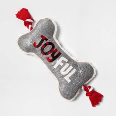 a dog bone ornament with the word joy on it and a red tassel