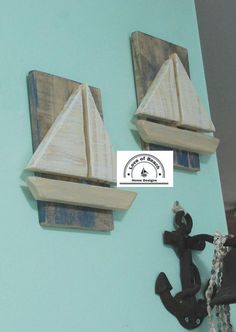 two wooden sailboats mounted to the side of a wall next to an anchor and hook