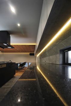 a kitchen with black counter tops and lights on the ceiling