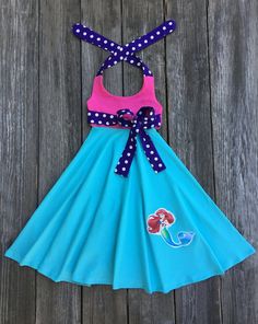 The Little Mermaid Ariel Dress This cute boutique Little Mermaid Ariel dress would be perfect for a Disney Princess birthday party, vacation, or just a fun day out in the sun. Dress is halter style made out of a aqua and hot pink knit with purple white polka dots accents with Ariel applique on front. Your little one will love twirling around showing off her dress on her special day. Ariel Mermaid Theme 100% Cotton Wash Warm tumble dry low iron if needed Made To Order MADE IN USA The Little Merma The Little Mermaid Costume, Birthday Toddler Girl, Bug Clothing, Little Mermaid Costume, Disney Princess Birthday Party, Polka Dot Birthday, Ariel Dress, Ariel Mermaid, Halter Dress Summer