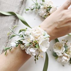 two hands are holding flowers on the table