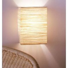 a lamp that is on the wall next to a wicker chair in a room