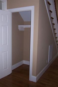 an empty room with a white door and some stairs in the corner, next to a brown wall