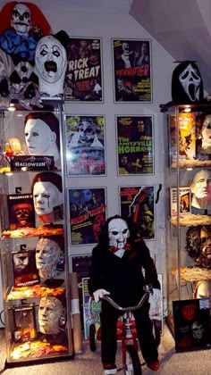 a person riding a bike in front of a display case with masks on the wall