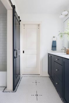 a white bathroom with black cabinets and a large mirror on the wall above the sink