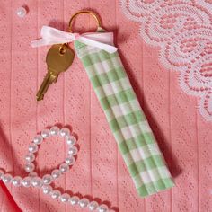 a keychain, bracelet and pearls are on a pink tablecloth with lace