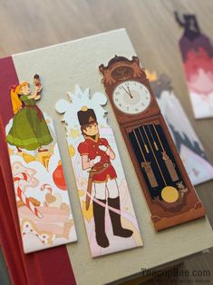 two bookmarks with cartoon characters on them sitting on a table next to each other