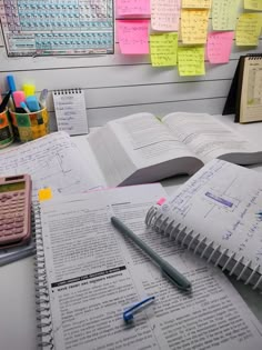 an open book sitting on top of a desk next to a calculator and pen