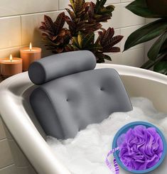 a bathtub filled with foam next to a candle and potted plant in the background