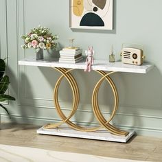 a console table with marble top and gold rings on the base, in front of a green wall