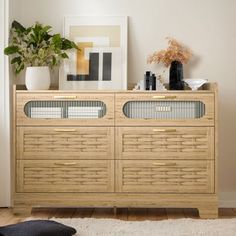 a wooden cabinet with glass doors and drawers in a living room next to a potted plant