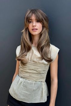 a woman with long hair standing in front of a wall