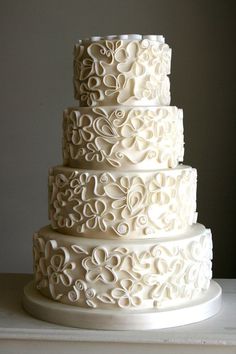 a three tiered white wedding cake with swirly icing on it's sides