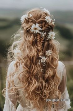 a woman with long curly hair and flowers in her hair is looking down at the ground