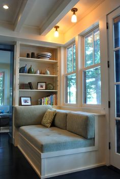 a couch sitting in front of a window next to a book shelf