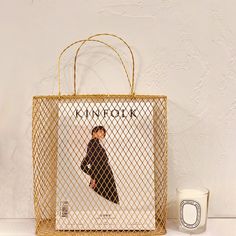 a shopping bag sitting on top of a table next to a cup and candle holder