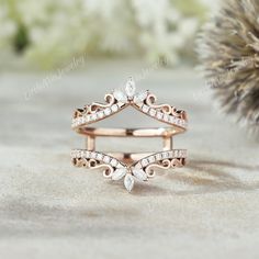 a rose gold wedding ring set with diamonds on the side and leaves in the middle