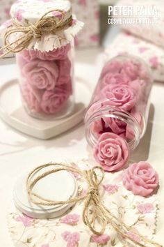 some pink flowers are in a glass jar on a table with tags and twine