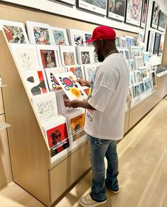 a man standing in front of a wall with pictures on it and holding a clipboard