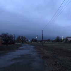 an empty road at dusk with power lines in the distance and buildings on either side