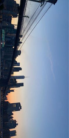 an airplane flying in the sky over a city with tall buildings and power lines at sunset