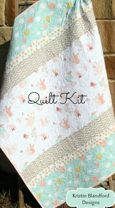 a quilted blanket hanging from the side of a brick wall with words quilt kit written on it