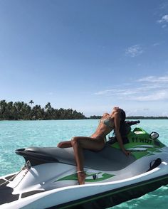 a woman laying on top of a jet ski in the ocean