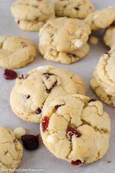 cookies with cranberries and white chocolate chips are on a baking sheet, ready to be eaten