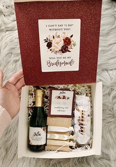 someone holding a bottle of wine in a box with some cards and other items inside