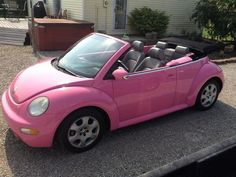 a pink convertible car parked in front of a house