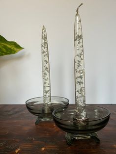 two glass candlesticks sitting on top of a wooden table