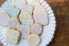 a white plate topped with cookies covered in pastel icing and polka dot shapes