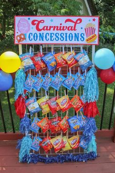 a candy bar with balloons and streamers on the fence for an outdoor carnival concesions display