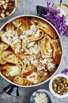 a pan filled with bread, nuts and other food on top of a table next to bowls