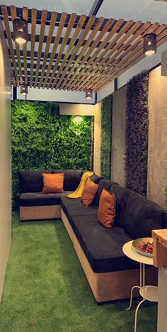 an outdoor living area with green grass and plants on the walls, couches and tables