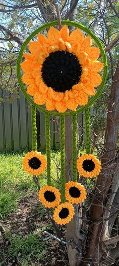 an orange and black sunflower wind chime hanging from a tree