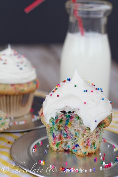 there is a cupcake with white frosting and sprinkles on it